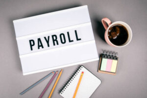 Payroll. Text In Light Box. Pink Coffee Mug On Gray Background